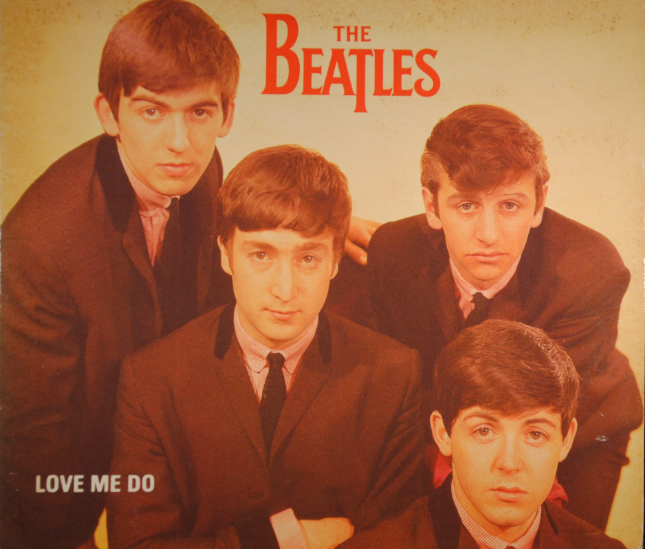 Early Beatles-style band performing on stage to a screaming crowd